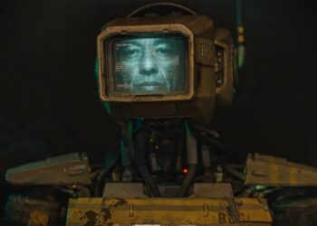 A humanoid robot with a monitor for a head displaying an actual human face.