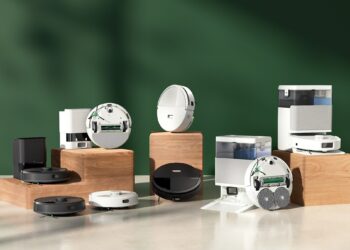 A family of robot vacuums posed on a green background.