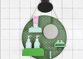 A shower organizer hanging from a shower nozzle with little shelves holding bottles.