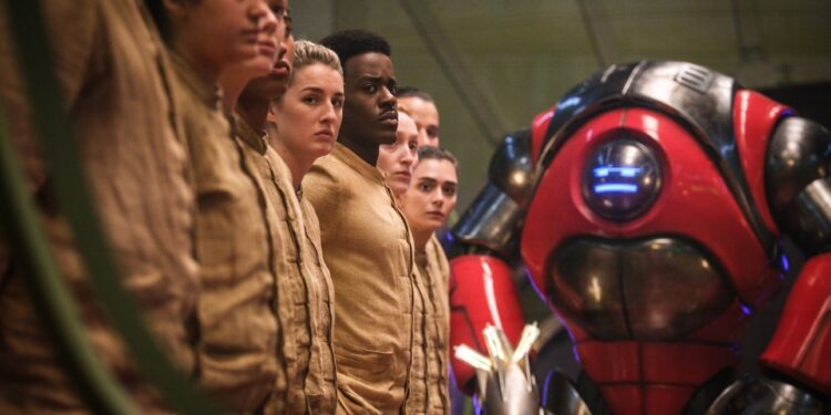 A group of people wearing all-tan outfits and standing in a line as a hulking robot leers at them .