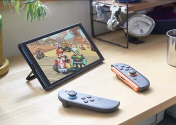 The Nintendo Switch 2 turned on with a Mario game playing and Joy Cons nearby on a desk.