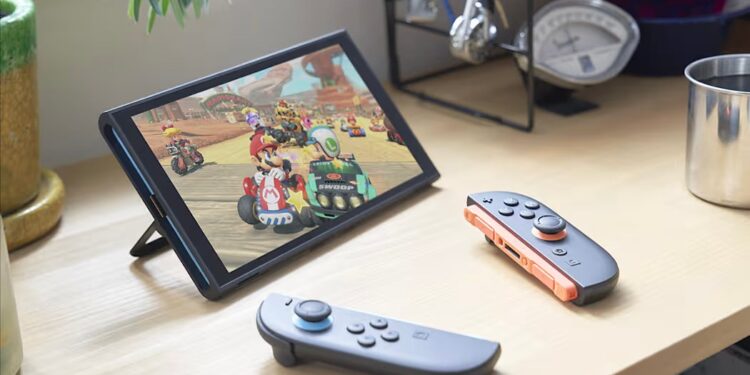 The Nintendo Switch 2 turned on with a Mario game playing and Joy Cons nearby on a desk.