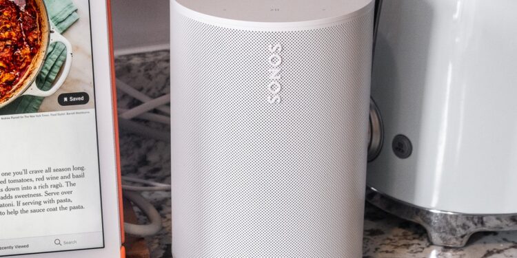 A photo of the Sonos Era 100 speaker in a kitchen setting beside an iPad and toaster.