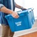 Person holding a plastic moving bin.
