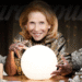 A woman gazes into a crystal ball surrounded by stacks of money.