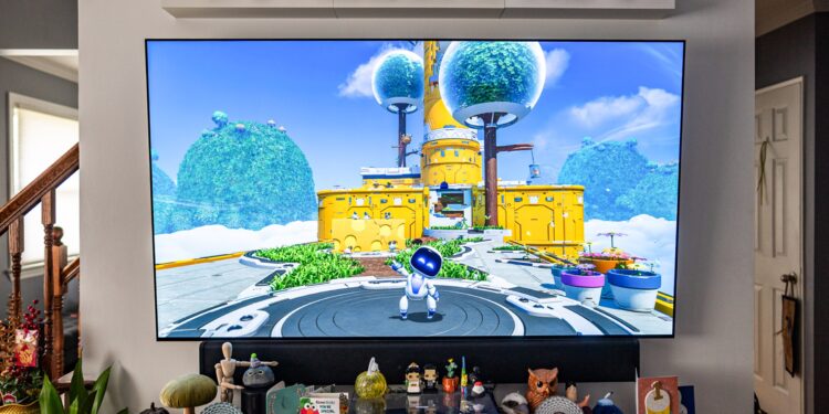 A TV set with a game on it, small figures lined up on a shelve above and a table top below.