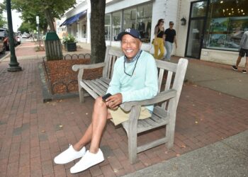 Russell Simmons sitting on a park bench, holding a phone.