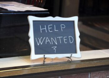 Help wanted sign in restaurant window.
