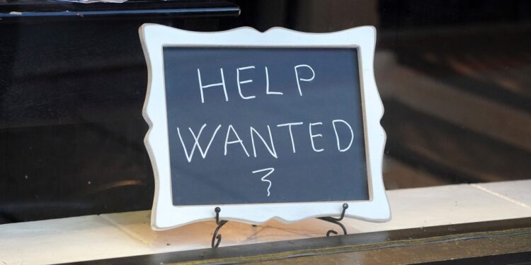 Help wanted sign in restaurant window.