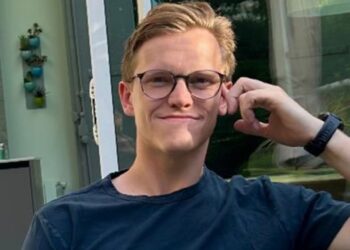 Young man wearing glasses and a dark t-shirt.