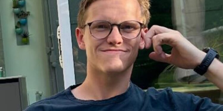 Young man wearing glasses and a dark t-shirt.