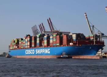 Large container ship Cosco Shipping Leo being towed into port.