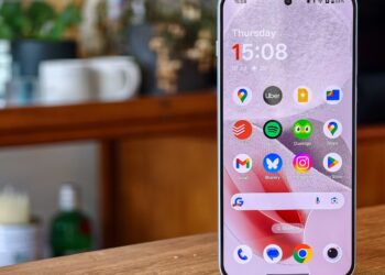Photo of the OnePlus Nord 5 on a wooden table, with the home screen in view
