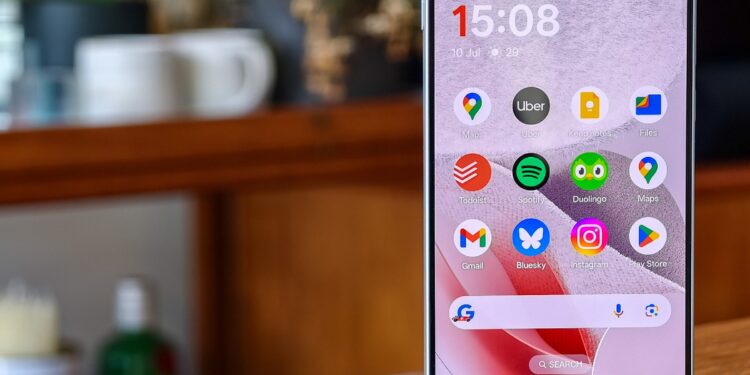 Photo of the OnePlus Nord 5 on a wooden table, with the home screen in view