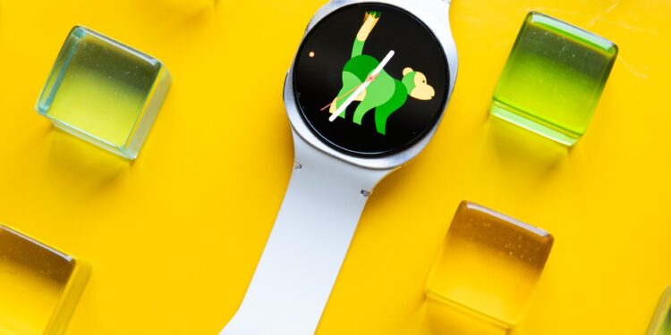 Wide view of the Samsung Galaxy Watch 8 on a yellow table with colorful green, yellow, orange, and pink acrylic blocks around it.