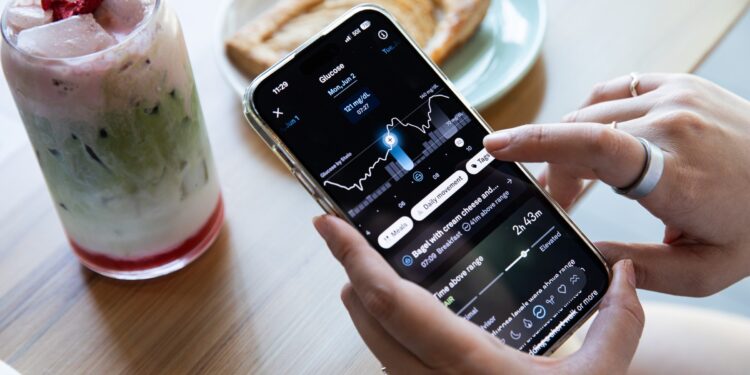 Person looking at their glucose levels in the Oura app with a strawberry matcha latte and a pastry in the background.