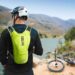 Biker rider wearing backpack with river and bike in background