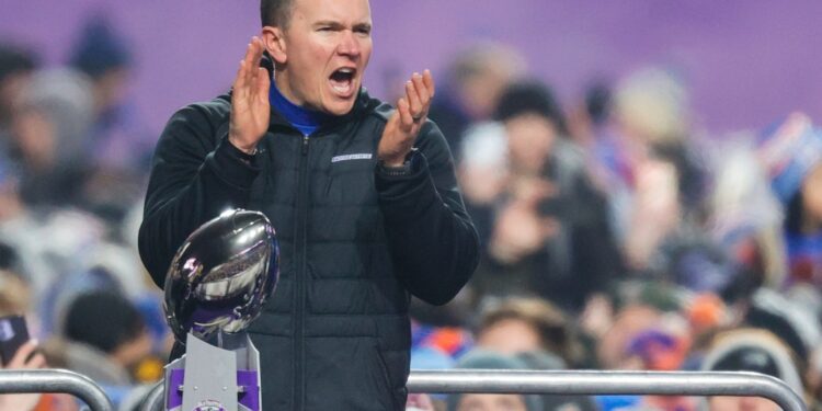 Boise State head coach celebrating with the Mountain West Championship trophy.