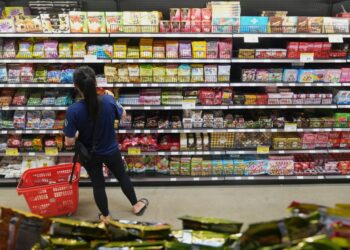 A shopper selects candy from a store shelf.