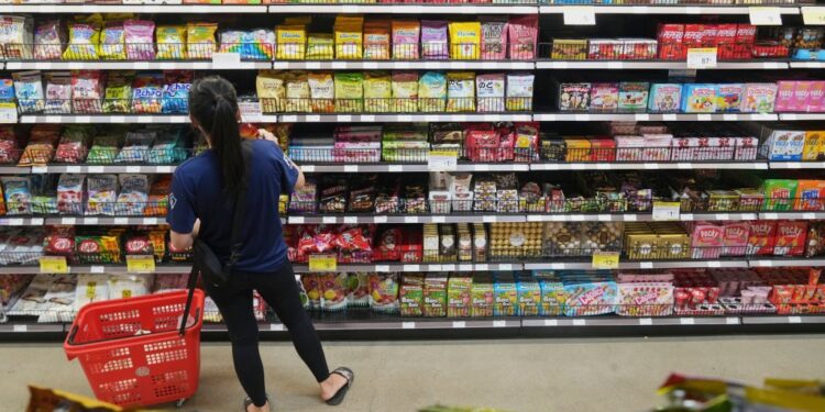 A shopper selects candy from a store shelf.