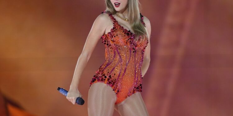 Taylor Swift performing on stage in an orange sequined bodysuit.