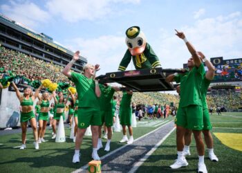 Oregon Ducks mascot being carried by students during a football game.