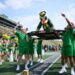 Oregon Ducks mascot being carried by students during a football game.