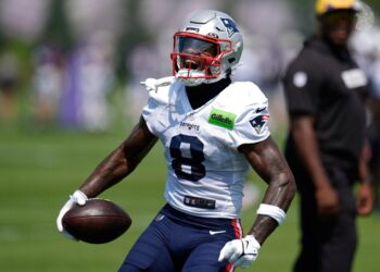New England Patriots player in uniform holding a football.