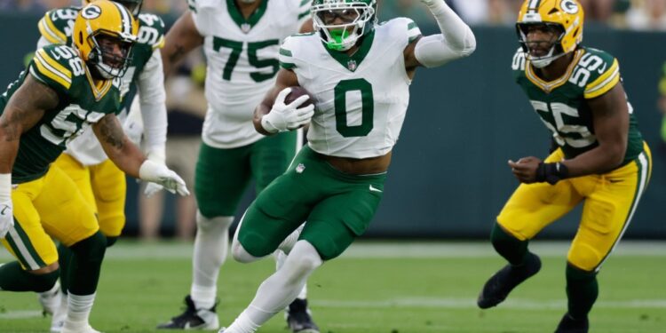 New York Jets player running with the football during a game against the Green Bay Packers.