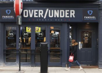 A woman walks past Over/Under sports bar, a FanDuel sportsbook location, in the Lincoln Park neighborhood of Chicago on Feb. 8, 2023.