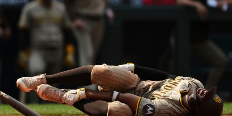 San Diego Padres player Xander Bogaerts in pain on the ground after hitting himself with his bat.