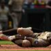 San Diego Padres player Xander Bogaerts in pain on the ground after hitting himself with his bat.