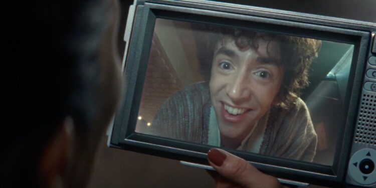 A shot of a woman holding a chunky tablet while having a video call with a grinning man displayed on the screen.