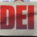 Person holding sign that says DEI.