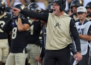 Wake Forest football coach instructing players.