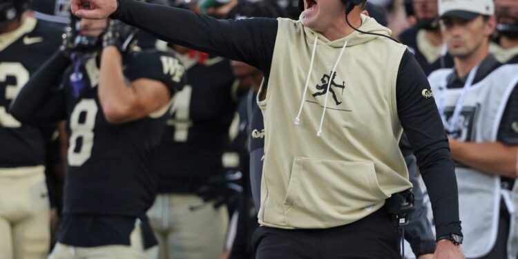 Wake Forest football coach instructing players.