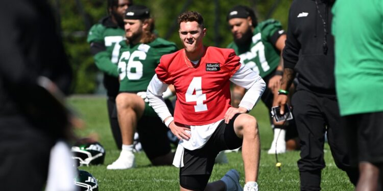 Brady Cook, wearing a red jersey with number 4, stretches during practice.