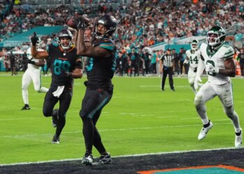 Miami Dolphins tight end Darren Waller catches a touchdown pass as Julian Hill celebrates and New York Jets' Andre Cisco defends.