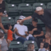 A baseball player hands a baseball to a young girl in the stands.