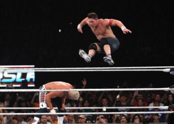 John Cena leaping over Cody Rhodes in a wrestling match.