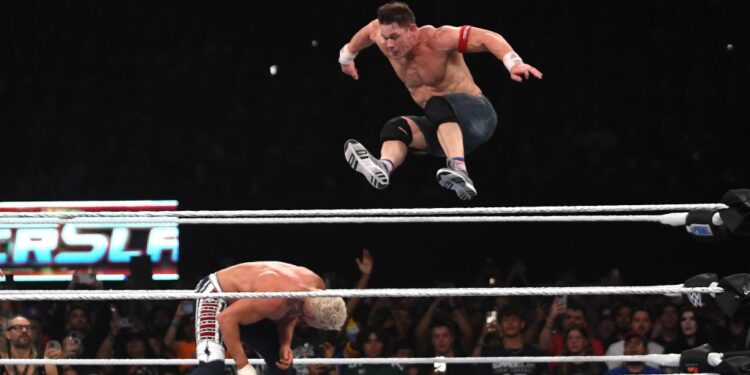 John Cena leaping over Cody Rhodes in a wrestling match.