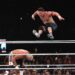 John Cena leaping over Cody Rhodes in a wrestling match.