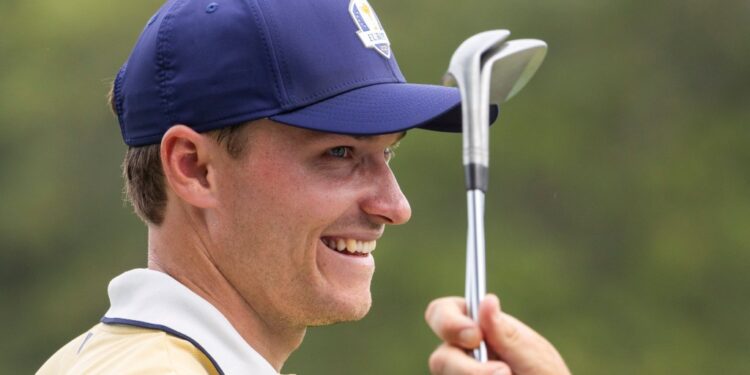 Ludvig Aberg smiling while holding golf clubs.
