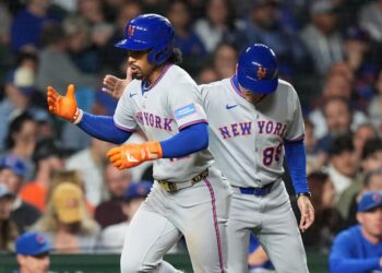 New York Mets' Francisco Lindor, left, is congratulated by third base coach Mike Sarbaugh after hitting a solo home run during the third inning of a baseball game against the Chicago Cubs in Chicago, Thursday, Sept. 25, 2025.