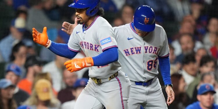 New York Mets' Francisco Lindor, left, is congratulated by third base coach Mike Sarbaugh after hitting a solo home run during the third inning of a baseball game against the Chicago Cubs in Chicago, Thursday, Sept. 25, 2025.