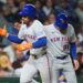 New York Mets' Francisco Lindor, left, is congratulated by third base coach Mike Sarbaugh after hitting a solo home run during the third inning of a baseball game against the Chicago Cubs in Chicago, Thursday, Sept. 25, 2025.