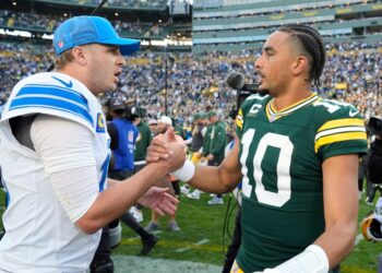 Two football players shaking hands on the field.