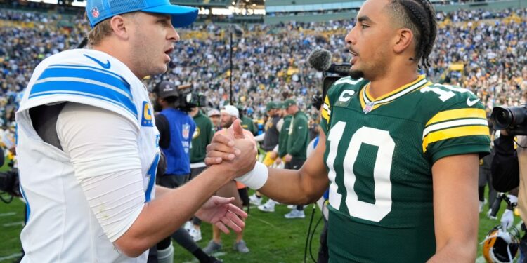 Two football players shaking hands on the field.