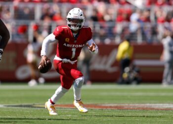 A Cardinals player running with the football on the field.