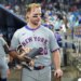 Pete Alonso in the dugout after a loss, wearing a gray Mets uniform, holding a notebook, gloves, and a bat.